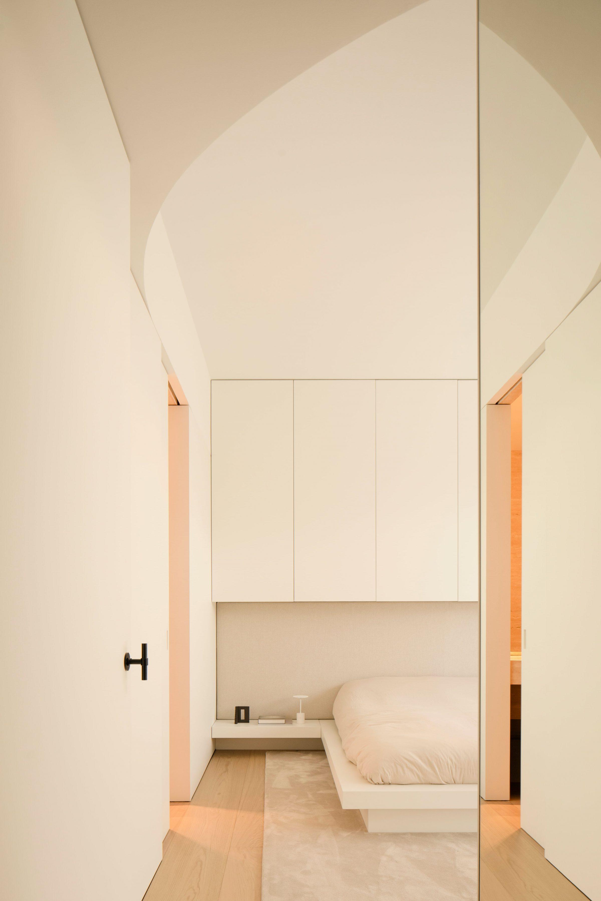 1928 Penthouse — bedroom seen through a curved ceiling soffit and mirror