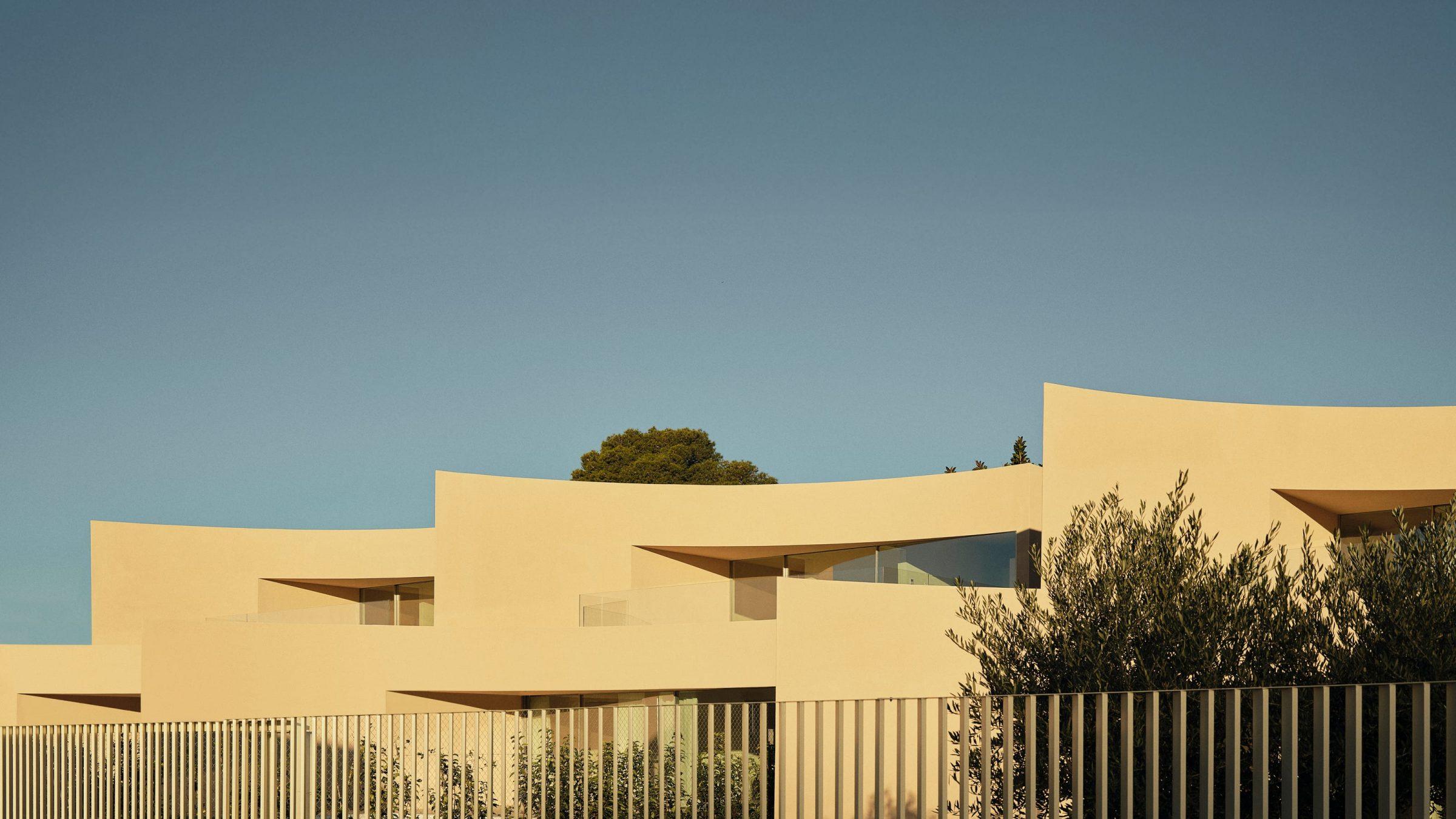 Alfinach Development — three houses read as a single composition, golden hour from the street