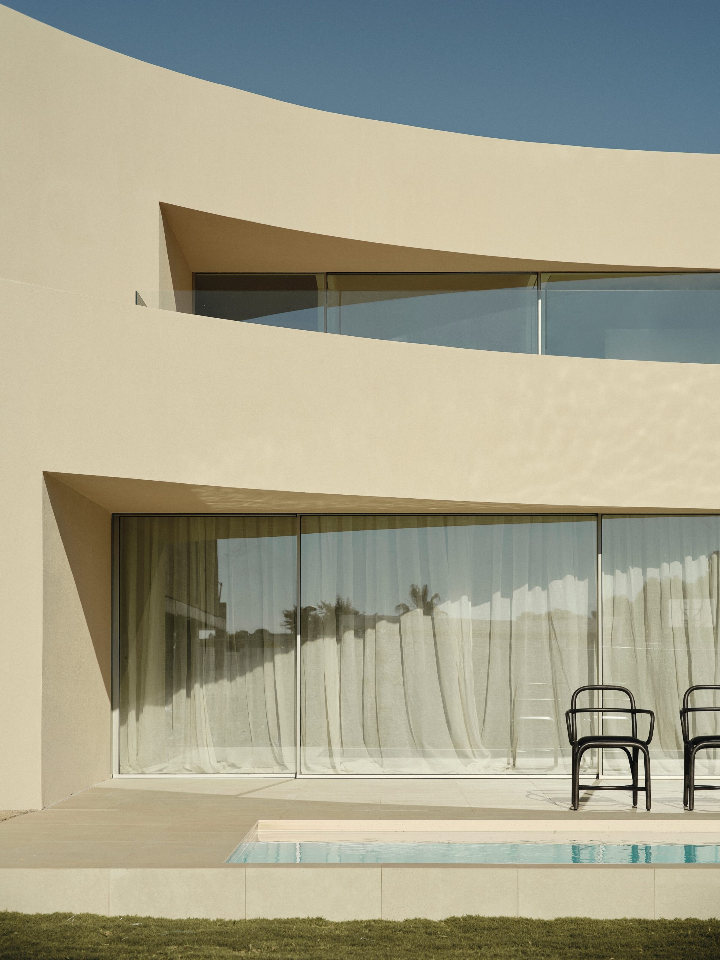 Alfinach Development — pool deck with two chairs and olive tree, curved overhang above