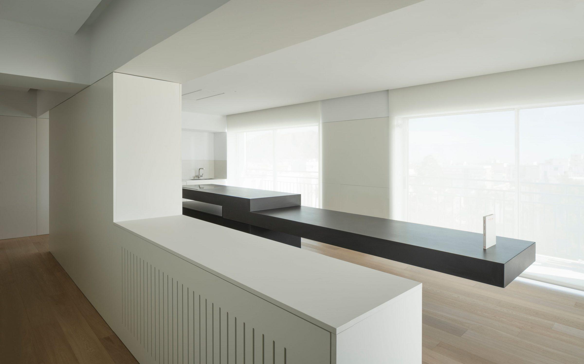 Orihuela Apartment, the dining island and rear wall lit by indirect warm cove lighting