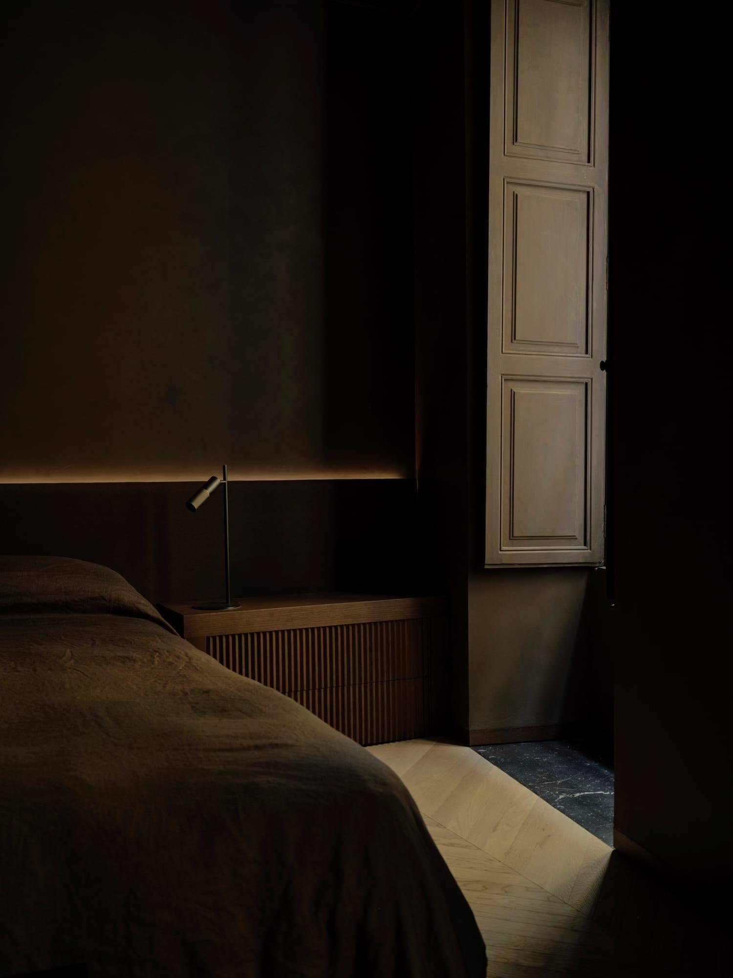 Ciutat Vella Apartment — dark oak bedroom with indirect cove light after dark