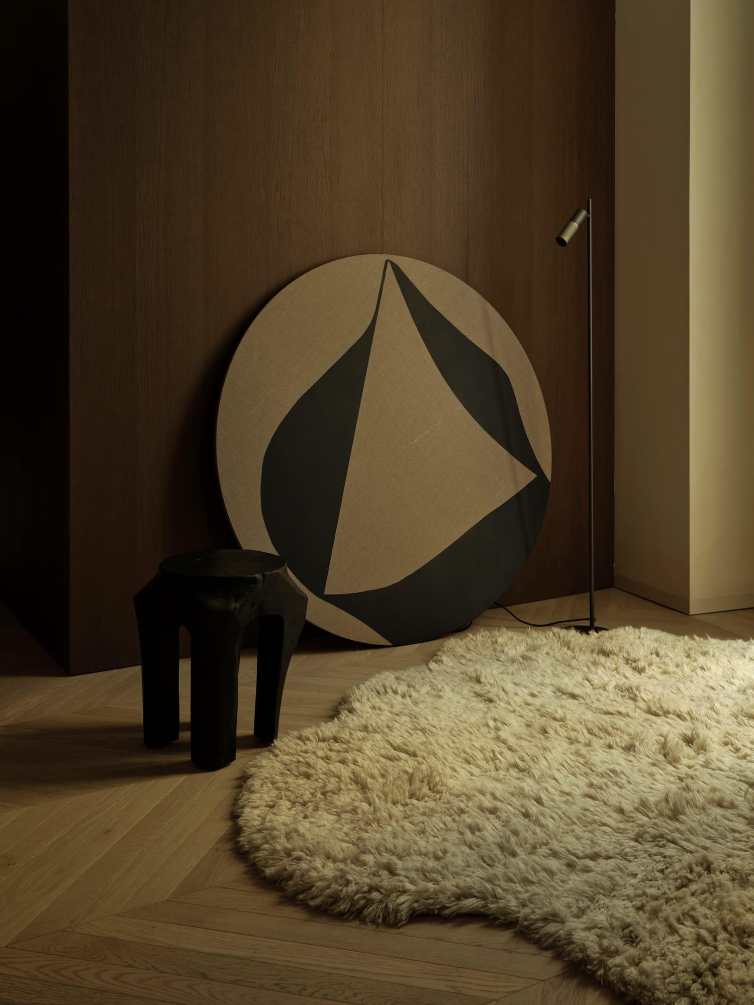 Ciutat Vella Apartment — round work by CLC Arte with a carved stool on a wool rug