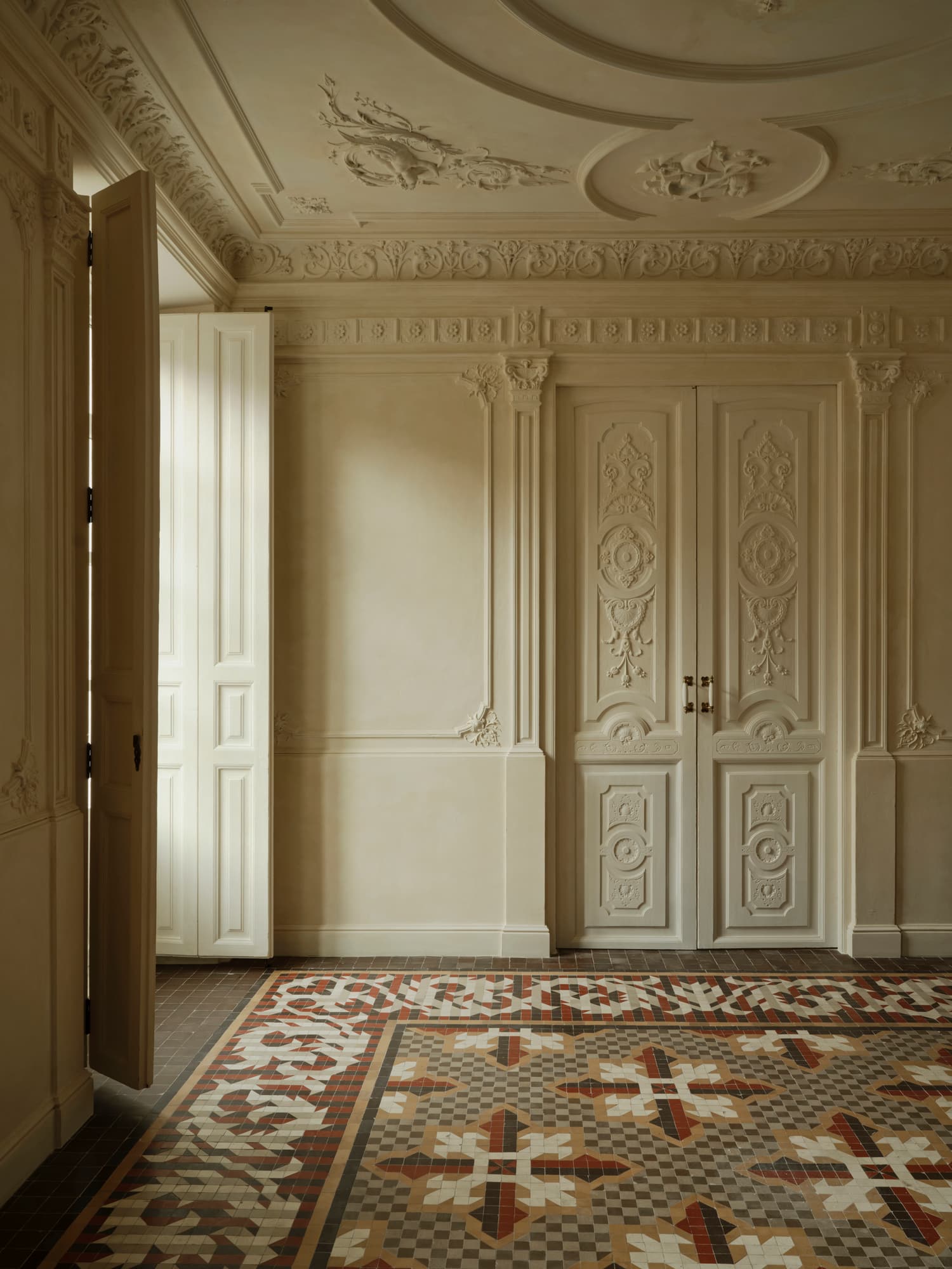 Ciutat Vella Apartment — carved lime-plaster panelling in raking daylight
