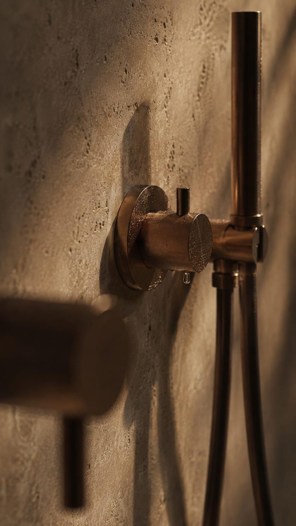 Moraleja CN6 House, bathroom detail: bronze shower fitting on travertine